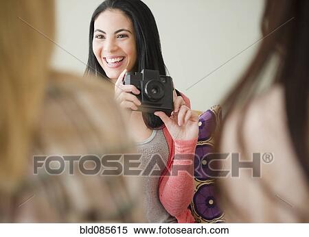 Stock Photography - Woman taking photograph of friends. Fotosearch