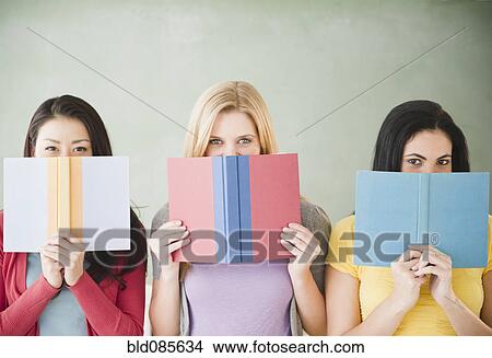 Picture - Women hiding behind books. Fotosearch