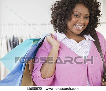 Stock Image - African American woman carrying shopping bag. Fotosearch
