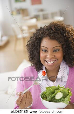 Stock Photography - African American woman eating salad. Fotosearch