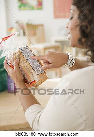 Stock Image - African American woman looking at loaf of bread. Fotosearch