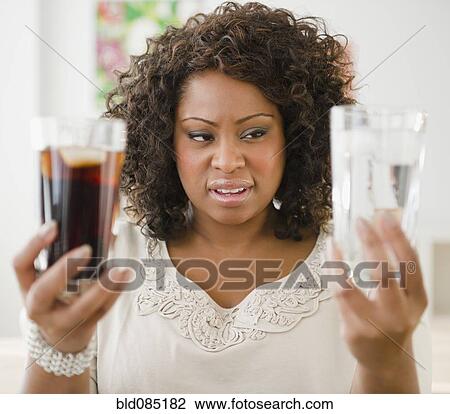 Stock Image - African American woman looking at water and soda. Fotosearch