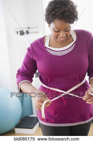 Stock Photography - African American woman measuring her waist. Fotosearch