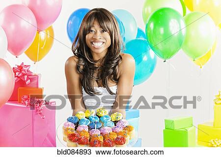 Stock Image - African American woman with birthday presents and cupcakes. Fotosearch