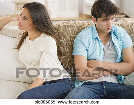 Stock Photography - Angry couple sitting on sofa together. Fotosearch