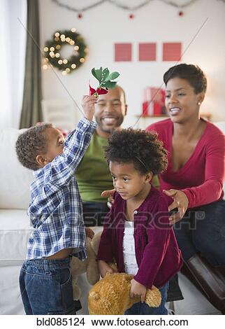 Picture - Black boy holding mistletoe over sisterís head. Fotosearch