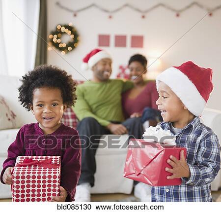 Stock Image - Black brother and sister holding Christmas gifts. Fotosearch