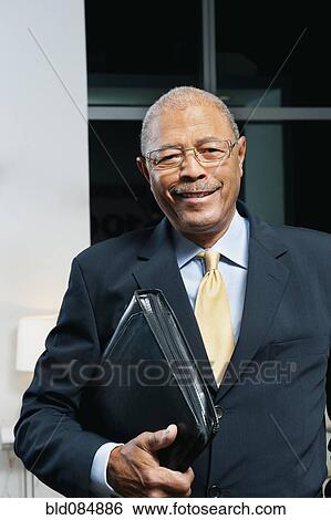 Stock Photograph - Black businessman in suit holding portfolio. Fotosearch