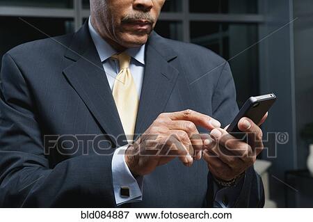 Stock Photo - Black businessman using cell phone. Fotosearch