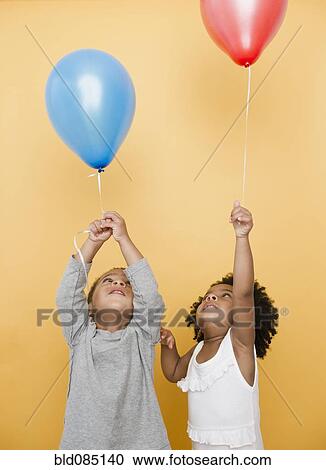 Stock Image - Black children holding helium balloons. Fotosearch