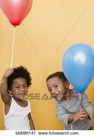 Stock Image - Black children holding helium balloons. Fotosearch