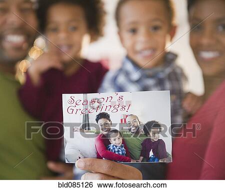 Stock Photograph - Black family holding Seasonís Greetings photograph. Fotosearch