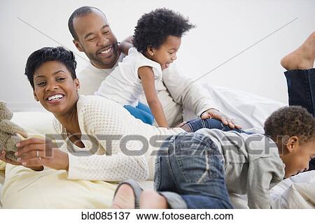Black family laying on bed together View Large Photo Image Stock Photo - Black family laying on bed together. Fotosearch