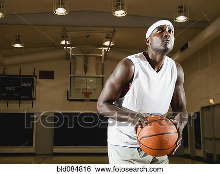 Stock Photograph - Black man shooting basketball on basketball court. Fotosearch