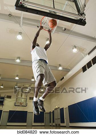 Stock Image - Black man shooting baskets on basketball court. Fotosearch