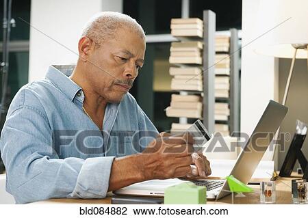 Stock Image - Black man shopping on line with credit card. Fotosearch