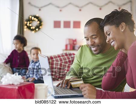 Stock Image - Black mother and father shopping online with credit card. Fotosearch