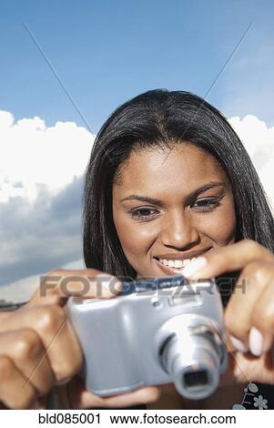 Stock Image - Black woman taking photograph with digital camera. Fotosearch