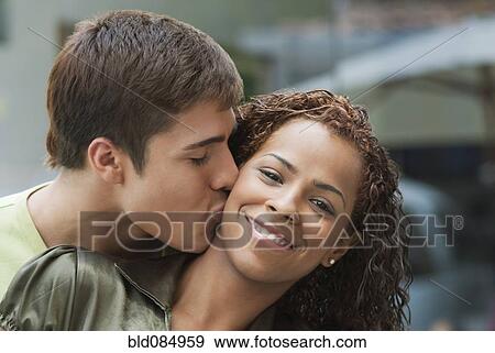 Stock Photo - Boyfriend kissing smiling girlfriend. Fotosearch
