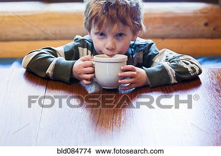 Picture - Caucasian boy drinking hot chocolate. Fotosearch