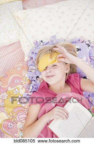 Stock Photography - Caucasian girl in sleep mask reading book. Fotosearch