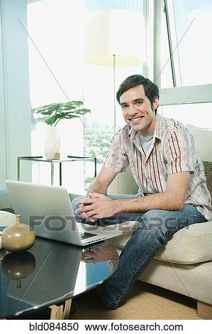 Caucasian man using laptop in living room View Large Photo Image Stock Image - Caucasian man using laptop in living room. Fotosearch
