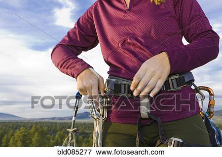Stock Photo - Caucasian woman preparing for rock climbing. Fotosearch