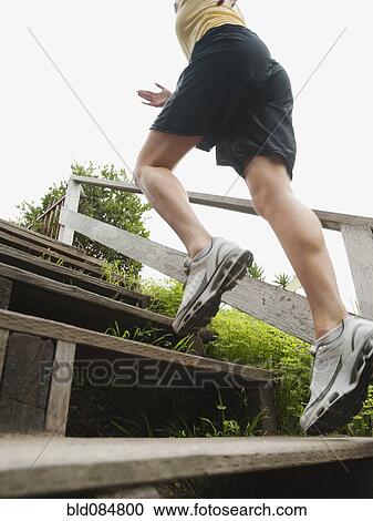Stock Image - Caucasian woman running up stairs for exercise. Fotosearch