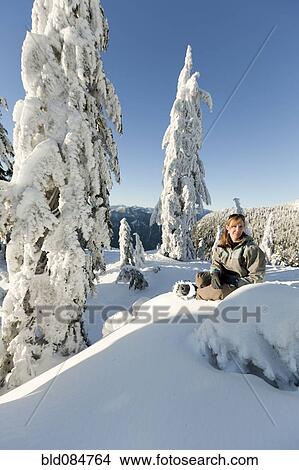 Picture - Caucasian woman snowshoeing in remote area taking break. Fotosearch