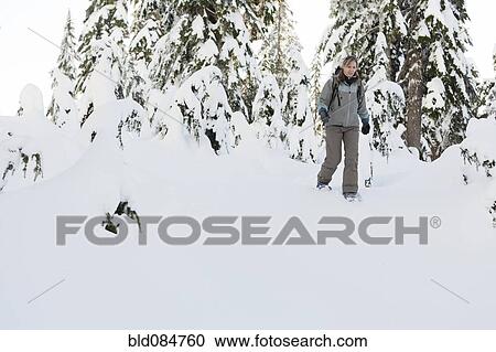 Stock Image - Caucasian woman snowshoeing in snow. Fotosearch