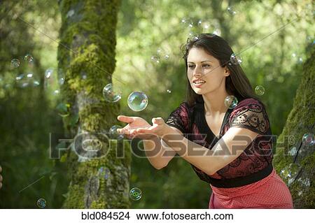 Caucasian woman trying to catch bubbles in her hands View Large Photo Image Picture - Caucasian woman trying to catch bubbles in her hands. Fotosearch