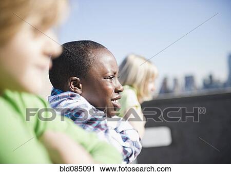 Stock Image - Children looking over rooftop railing. Fotosearch