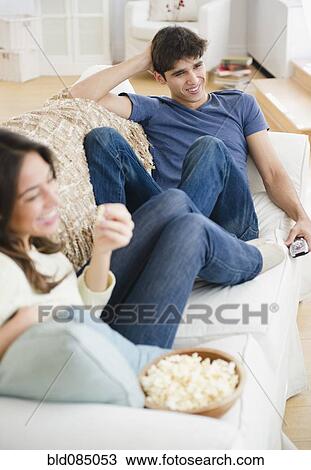 Stock Image - Couple eating popcorn and watching television. Fotosearch