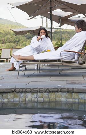 Stock Image - Couple enjoying breakfast near swimming pool. Fotosearch