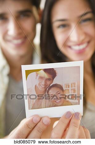 Stock Photo - Couple holding photograph of themselves. Fotosearch