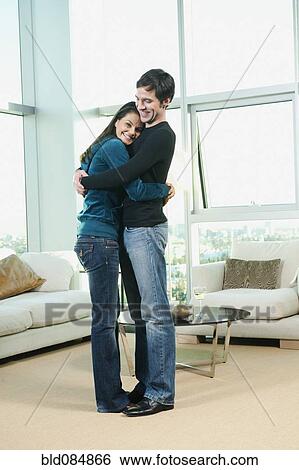 Stock Photograph - Couple hugging in living room. Fotosearch
