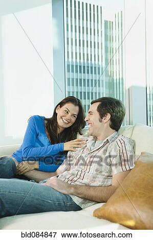 Couple laughing together on sofa View Large Photo Image Stock Photo - Couple laughing together on sofa. Fotosearch