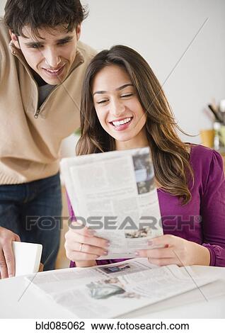 Couple looking at newspaper together View Large Photo Image Stock Image - Couple looking at newspaper together. Fotosearch