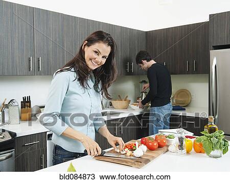 Stock Image - Couple making dinner together in kitchen. Fotosearch