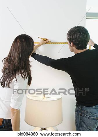 Couple marking wall with pencil and measuring tape View Large Photo Image Stock Image - Couple marking wall with pencil and measuring tape. Fotosearch