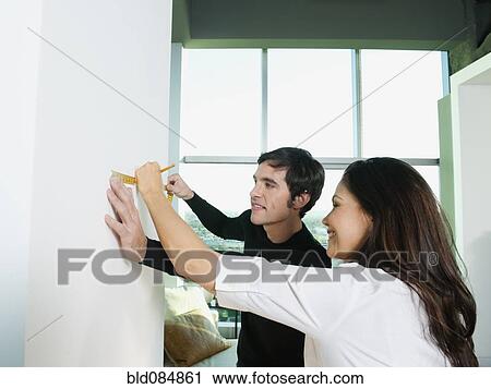 Couple marking wall with pencil and measuring tape View Large Photo Image Stock Image - Couple marking wall with pencil and measuring tape. Fotosearch