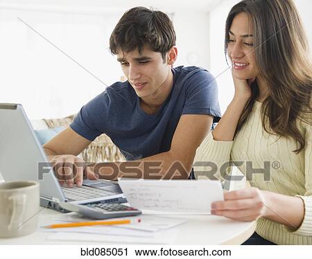 Stock Image - Couple paying bills together online. Fotosearch