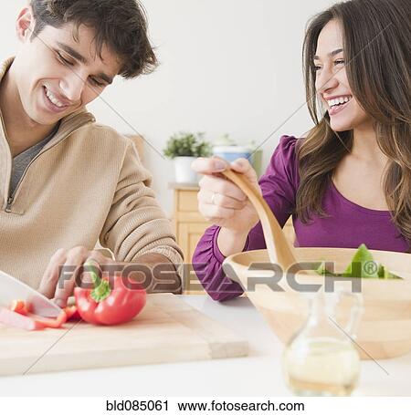Stock Image - Couple preparing salad together. Fotosearch