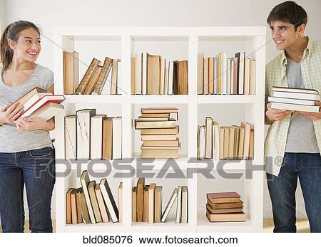 Stock Photograph - Couple with books standing near bookshelf. Fotosearch