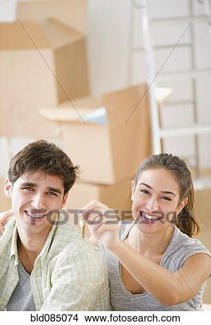 Picture - Excited couple holding keys to new home. Fotosearch