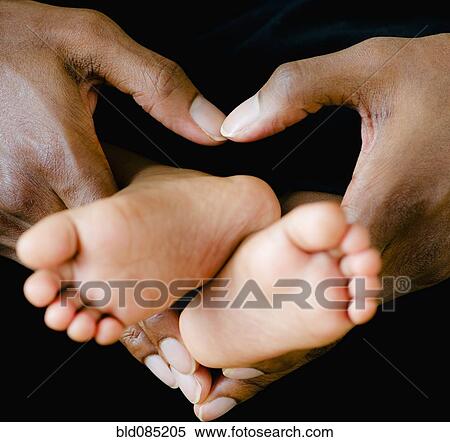 Stock Photography - Fatherís hands holding tiny baby feet. Fotosearch