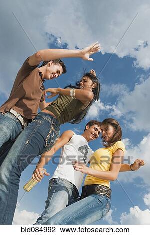 Stock Image - Friends drinking beer and dancing together. Fotosearch