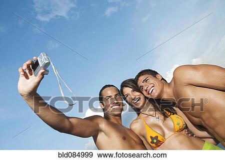 Stock Photo - Friends in bathing suits taking self-portrait with digital camera. Fotosearch