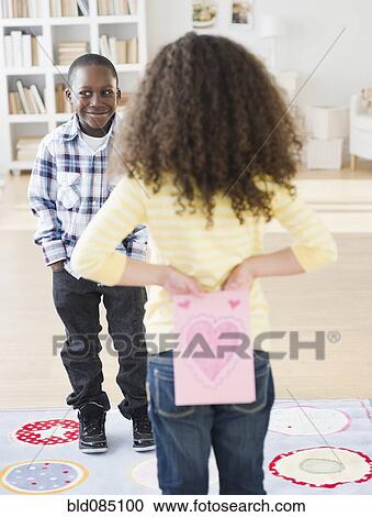 Stock Image - Girl holding Valentine card behind her back. Fotosearch