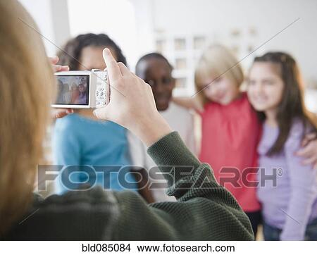 Girl taking photograph of friends with digital camera View Large Photo Image Picture - Girl taking photograph of friends with digital camera. Fotosearch